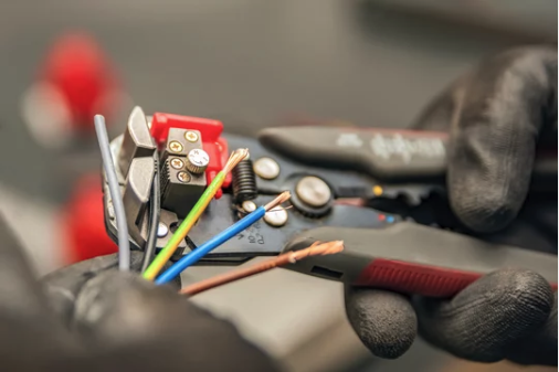 Electrician stripping multi-colored industrial wires using precision wire strippers for pump control system installation – RPM Industrial