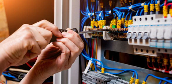 Technician performing industrial electrical panel wiring and maintenance on a pump control system with labeled terminals and blue wires – RPM Industrial